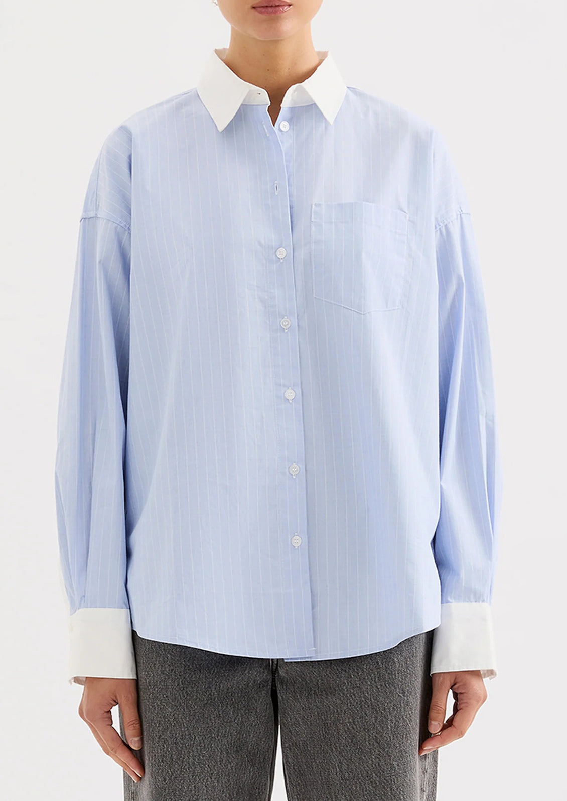 Light blue striped shirt with white collar and cuffs worn by a person on a white background.