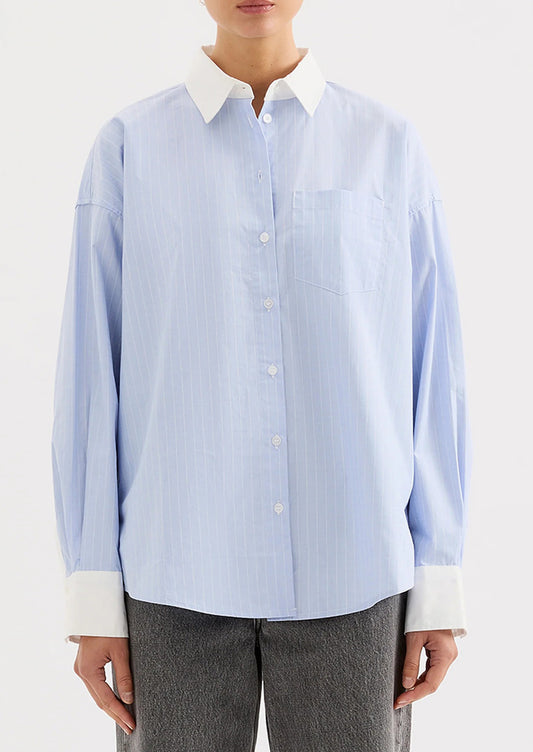 Light blue striped shirt with white collar and cuffs worn by a person on a white background.