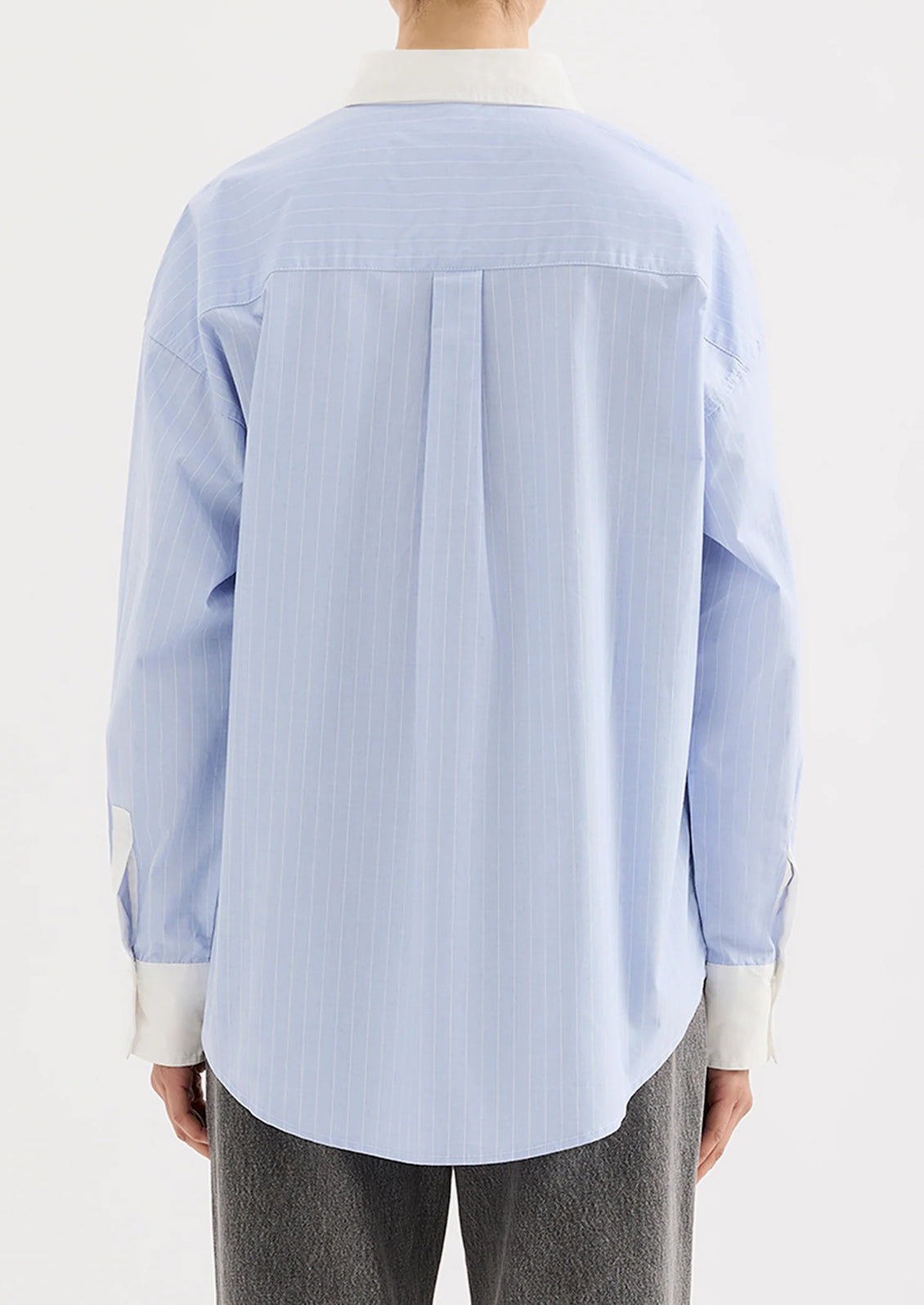 Light blue striped shirt with white collar and cuffs worn by a person on a white background.