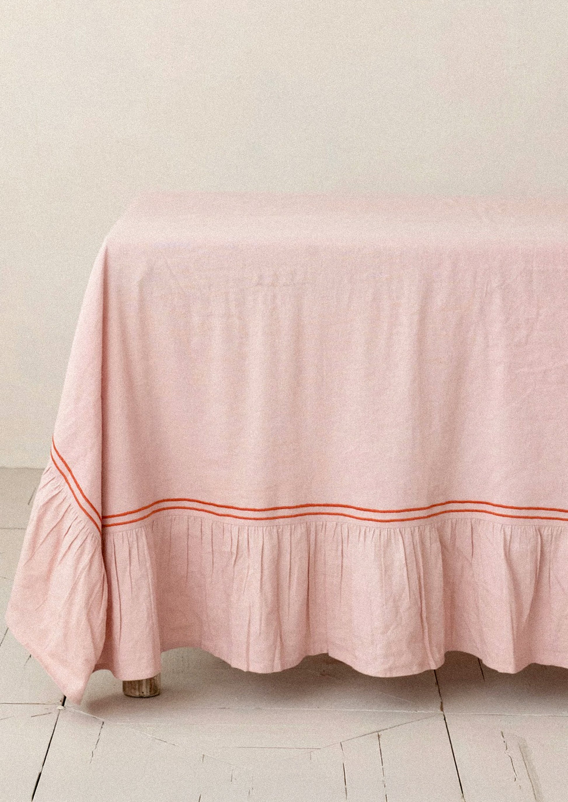 Pink tablecloth with a red trim on a wooden table against a light background