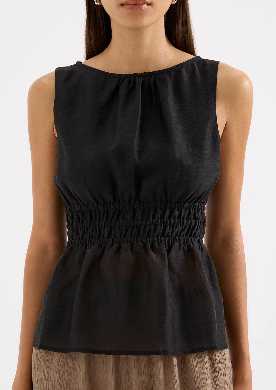 Black sleeveless top worn by a model on a white background