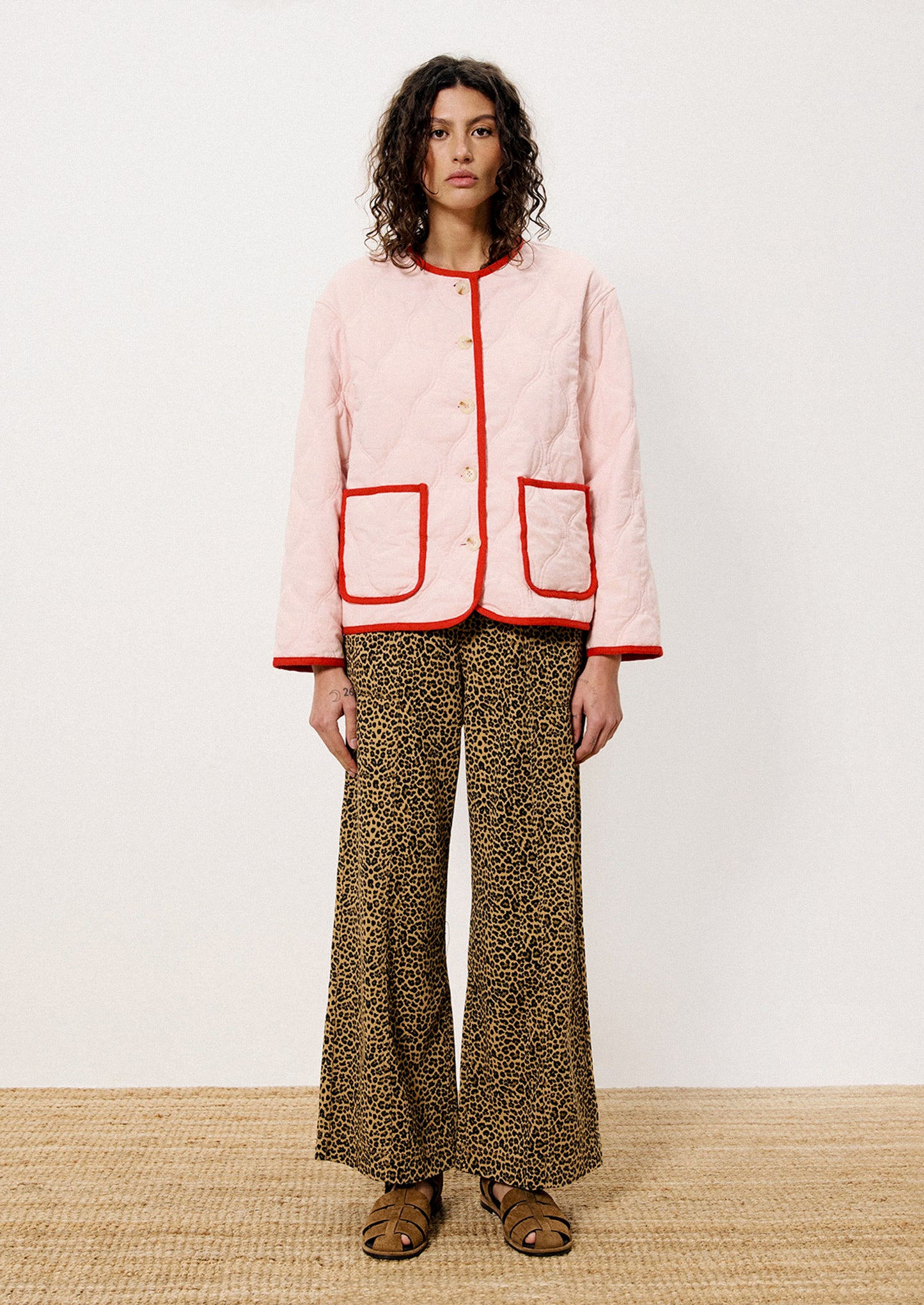 A person wearing a pink quilted jacket with red trim.