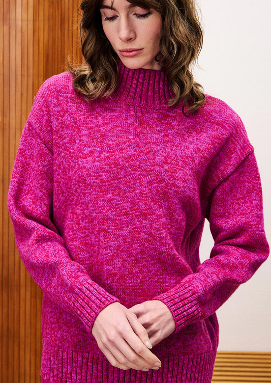 Person wearing a bright pink sweater against a wooden panel background
