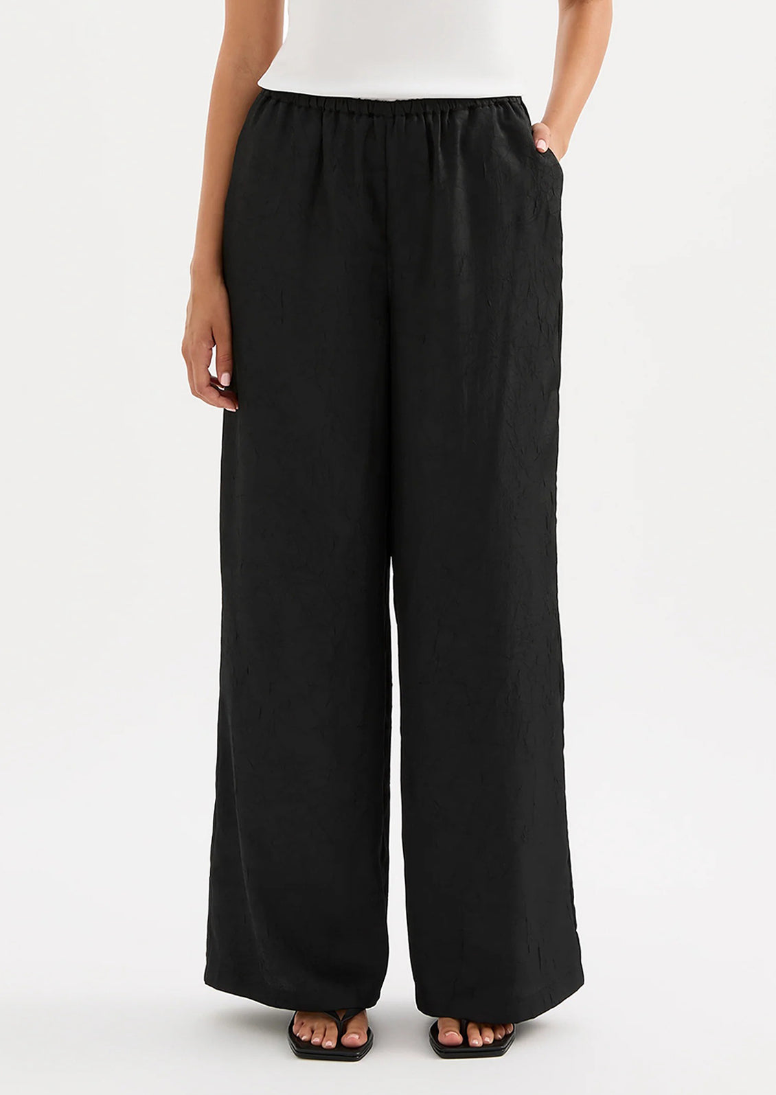Person wearing black wide-leg pants on a white background
