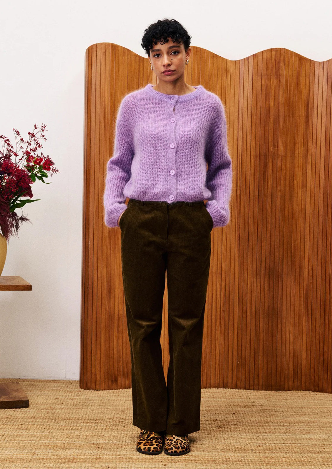 A woman wearing a cardigan sweater in medium purple color.