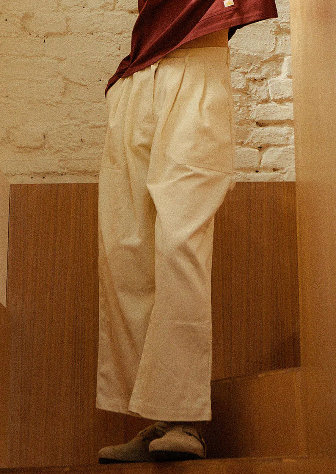 A person wearing a pair of workwear-inspired pants in ecru color.