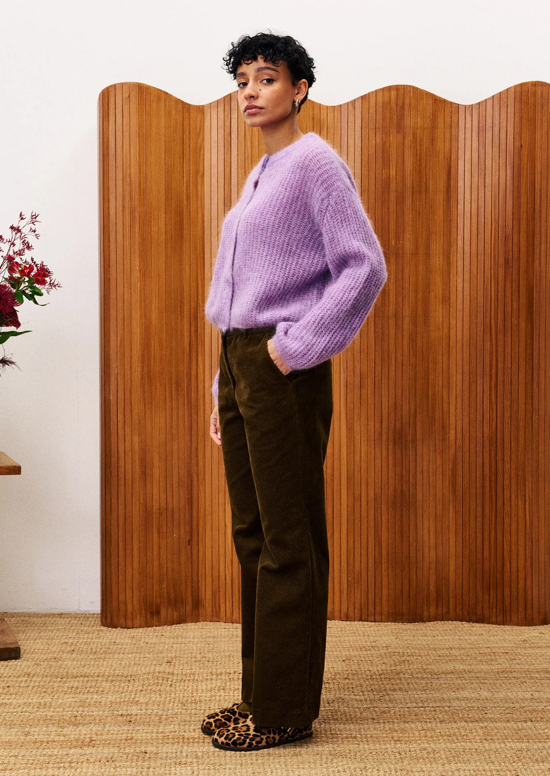 A woman wearing a cardigan sweater in medium purple color.