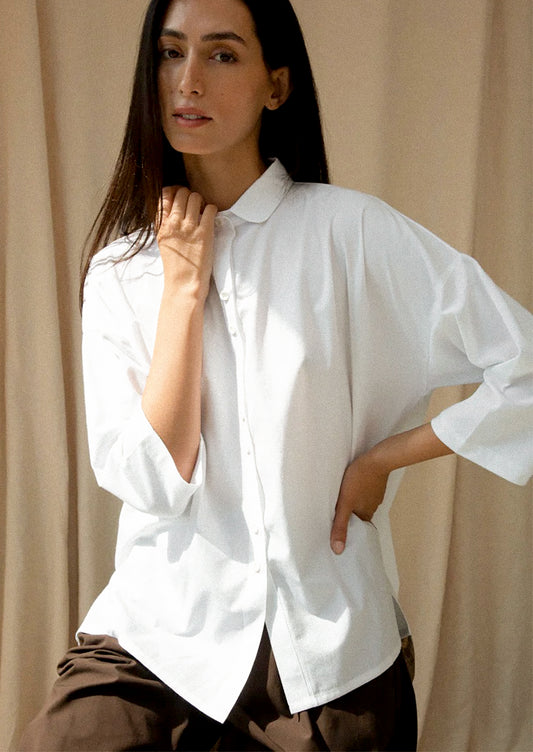 Woman wearing a white shirt against a beige curtain background