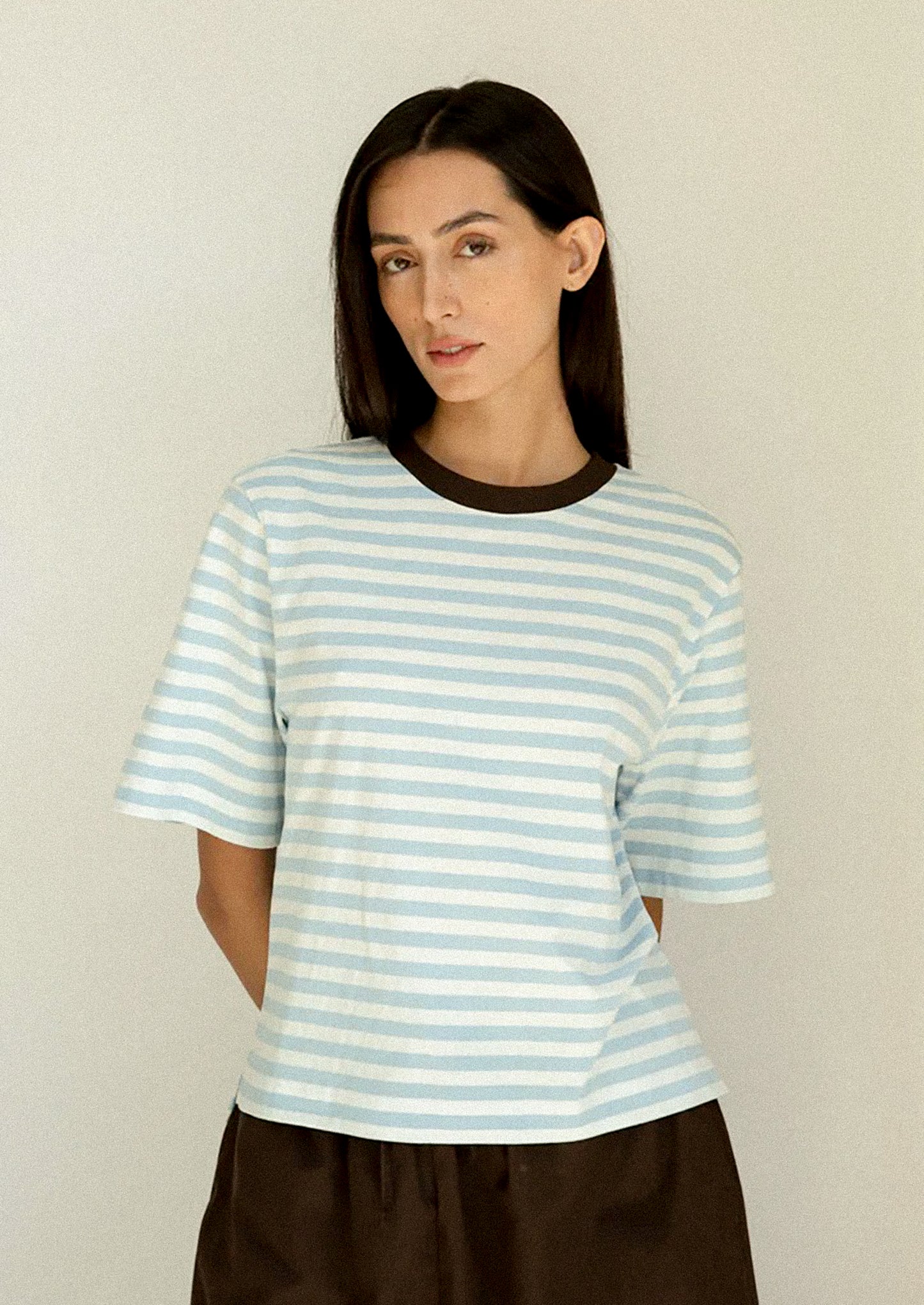 Woman wearing a light blue and white striped shirt against a plain background