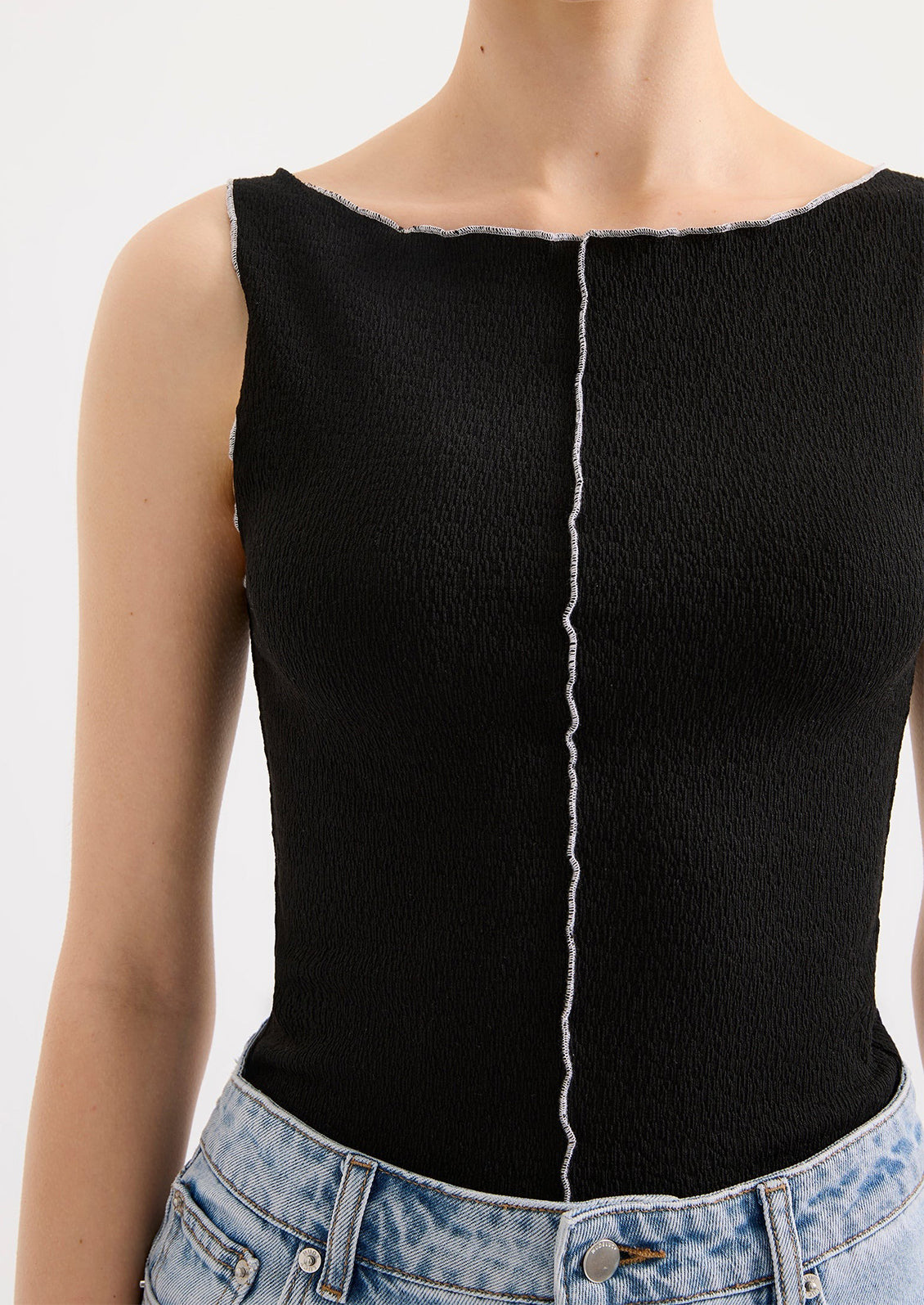 Black sleeveless top with a white stripe worn by a person on a white background