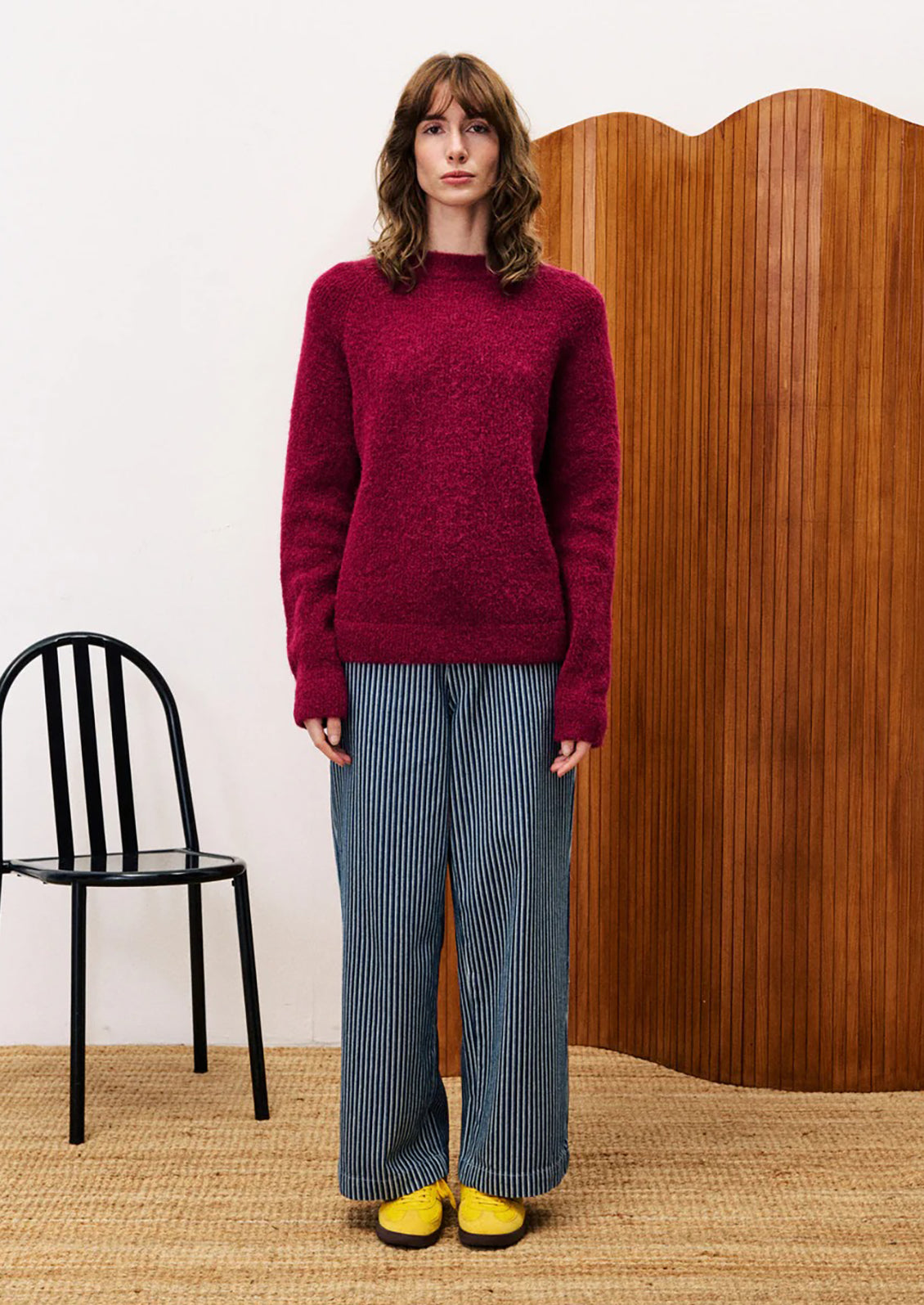 A woman wearing a knit sweater in vibrant burgundy color.