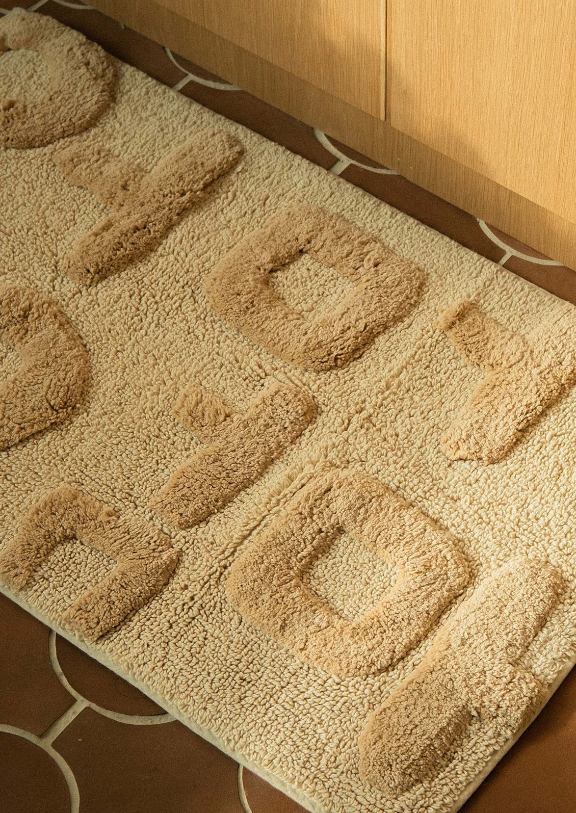 Beige textured bath mat on a tiled floor