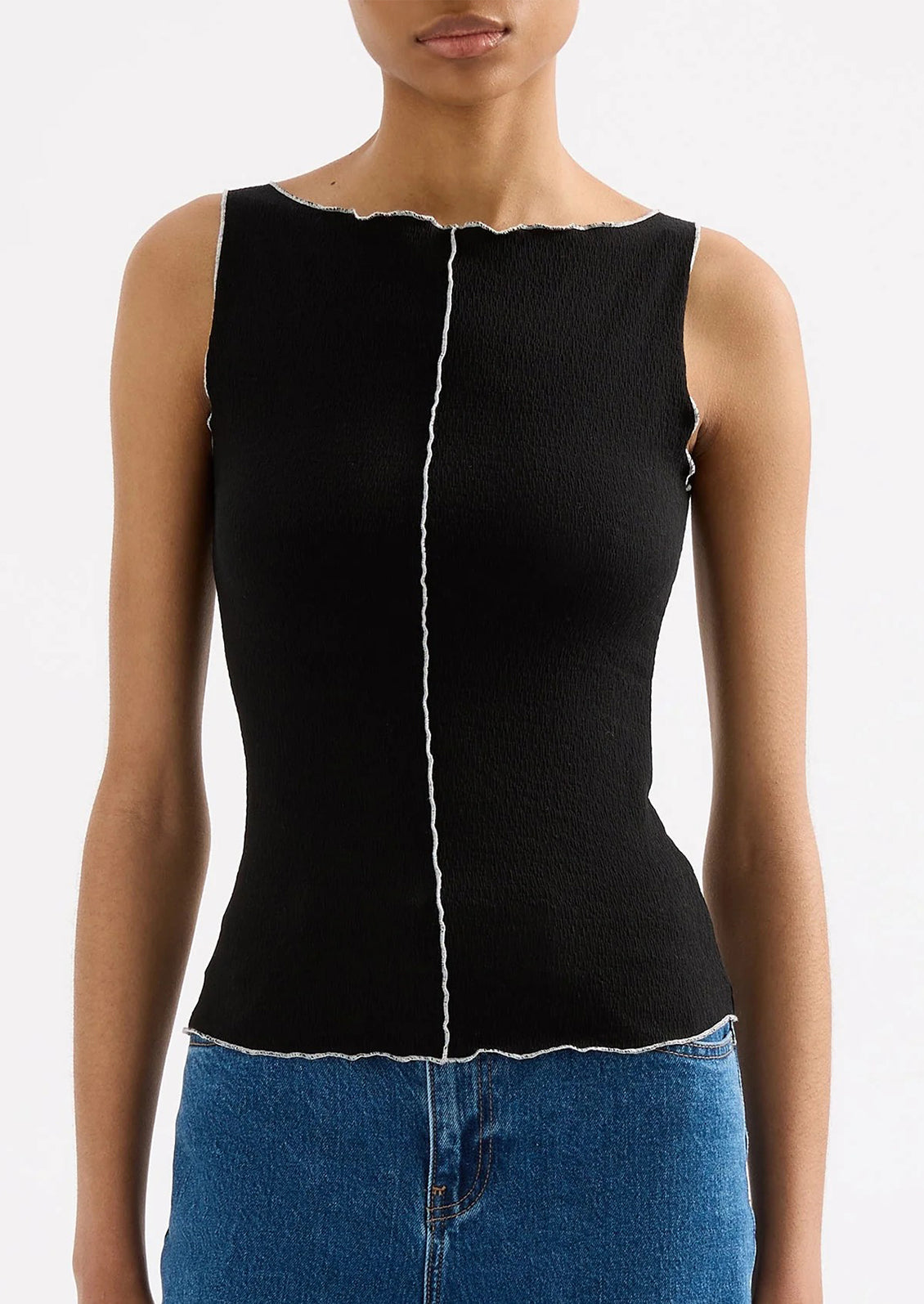 Black sleeveless top with white trim worn by a person on a white background