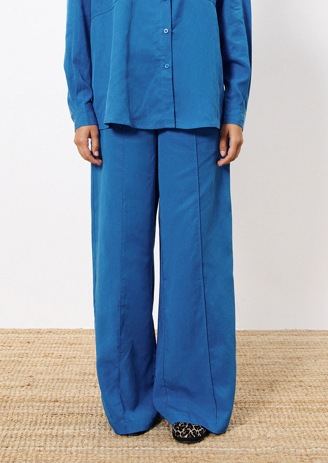 Person wearing a blue outfit with wide-leg pants on a neutral background