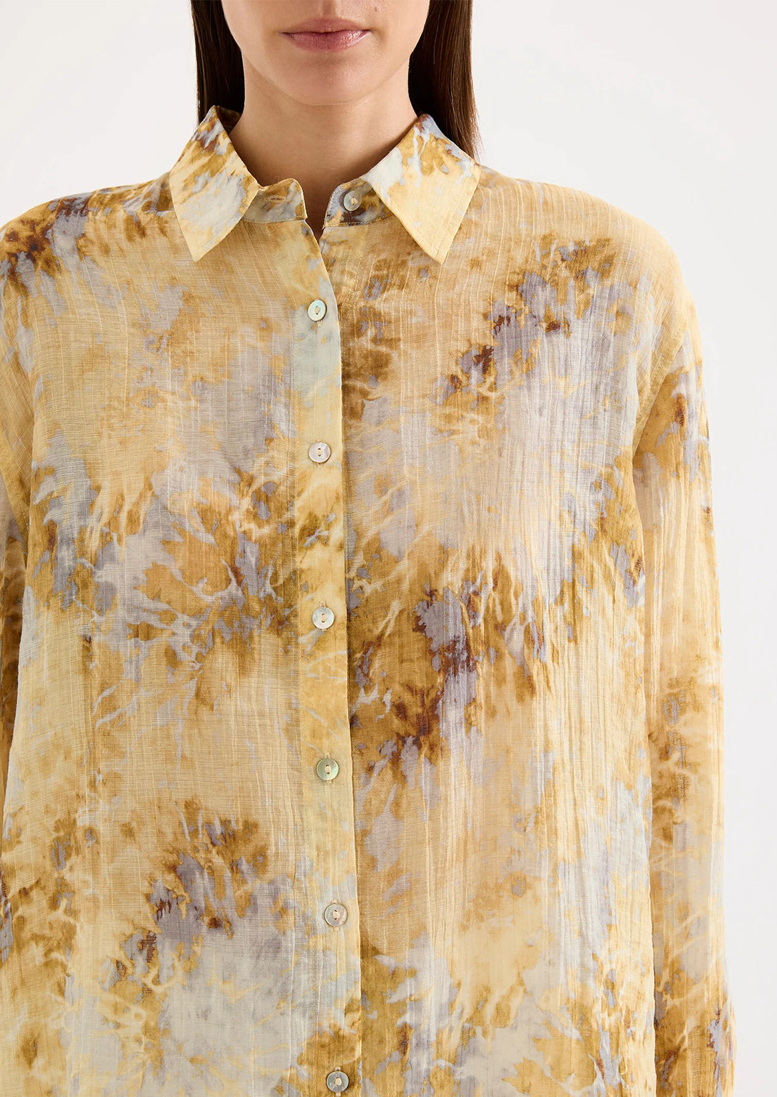 Woman wearing a yellow tie dye blouse against a white background