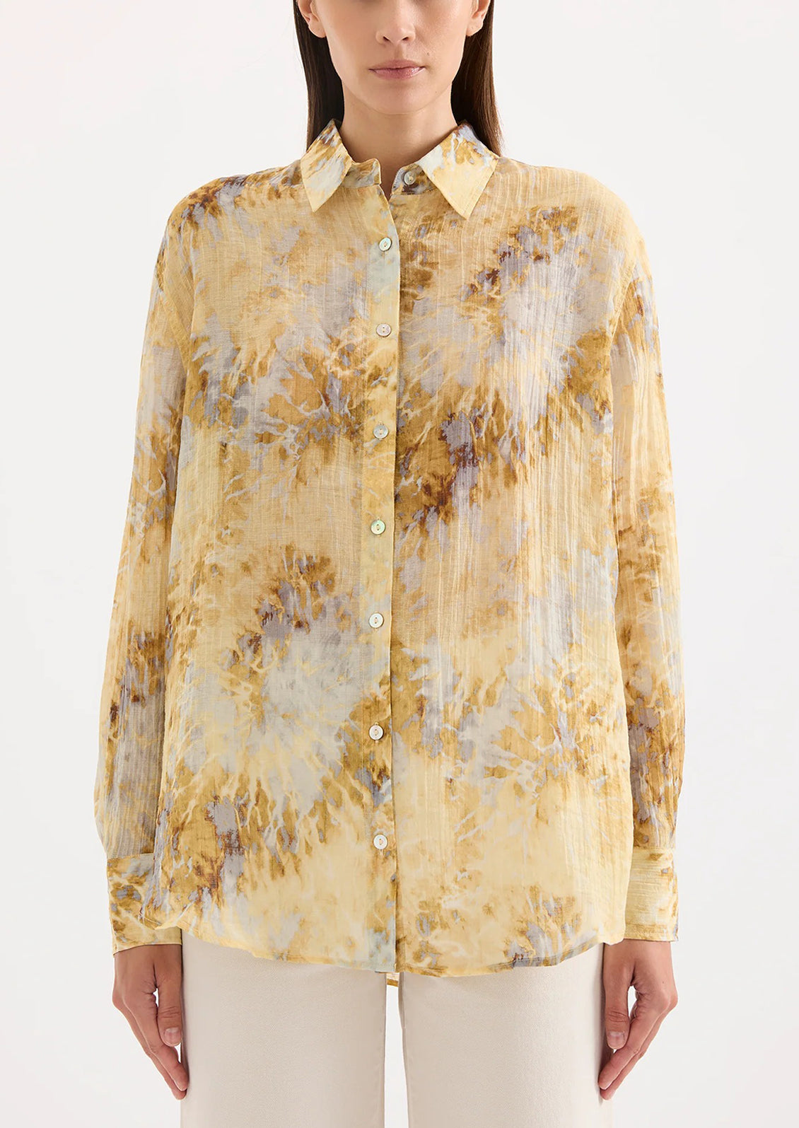 Woman wearing a yellow tie dye blouse against a white background