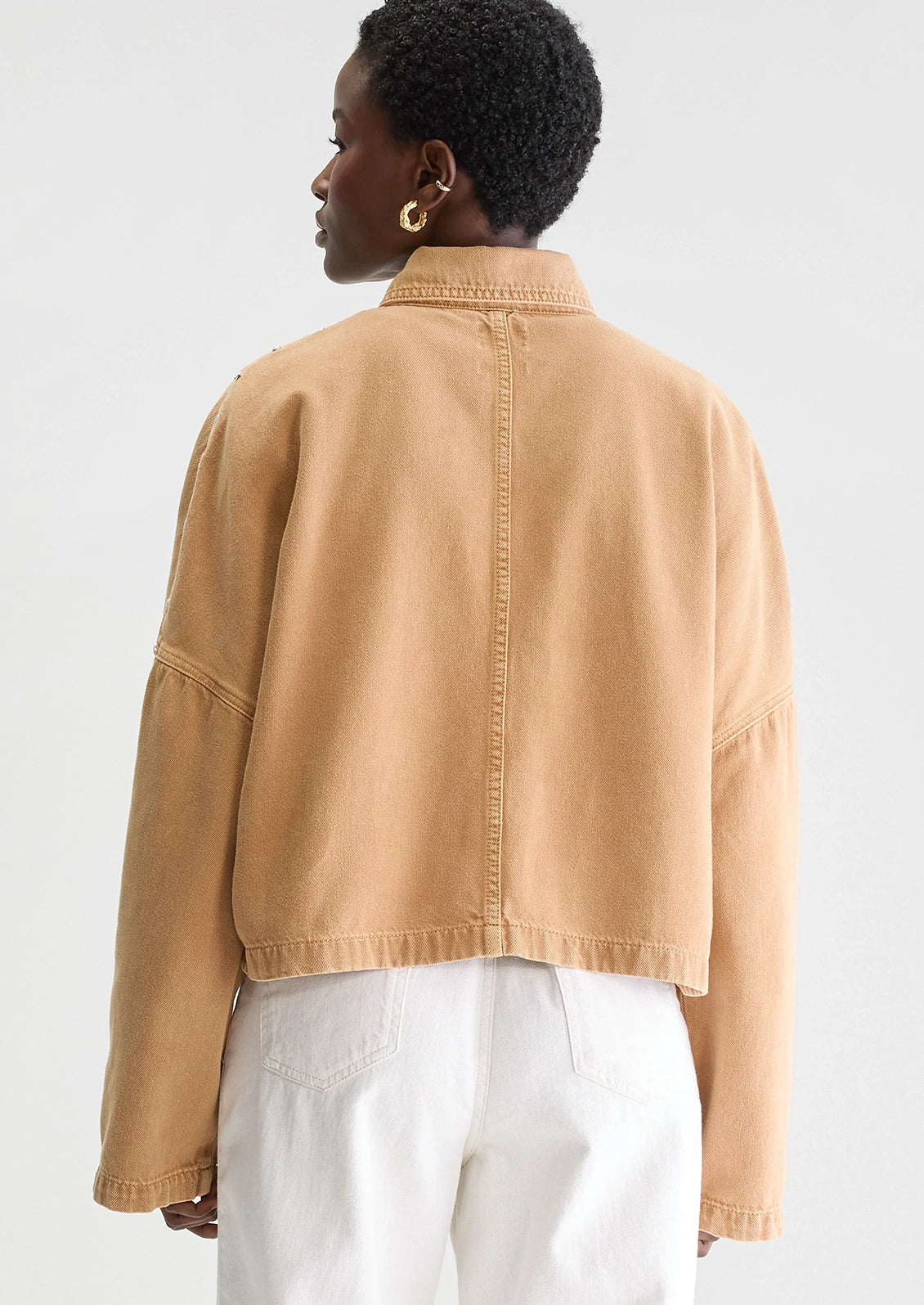 Person wearing a tan jacket with studded details.