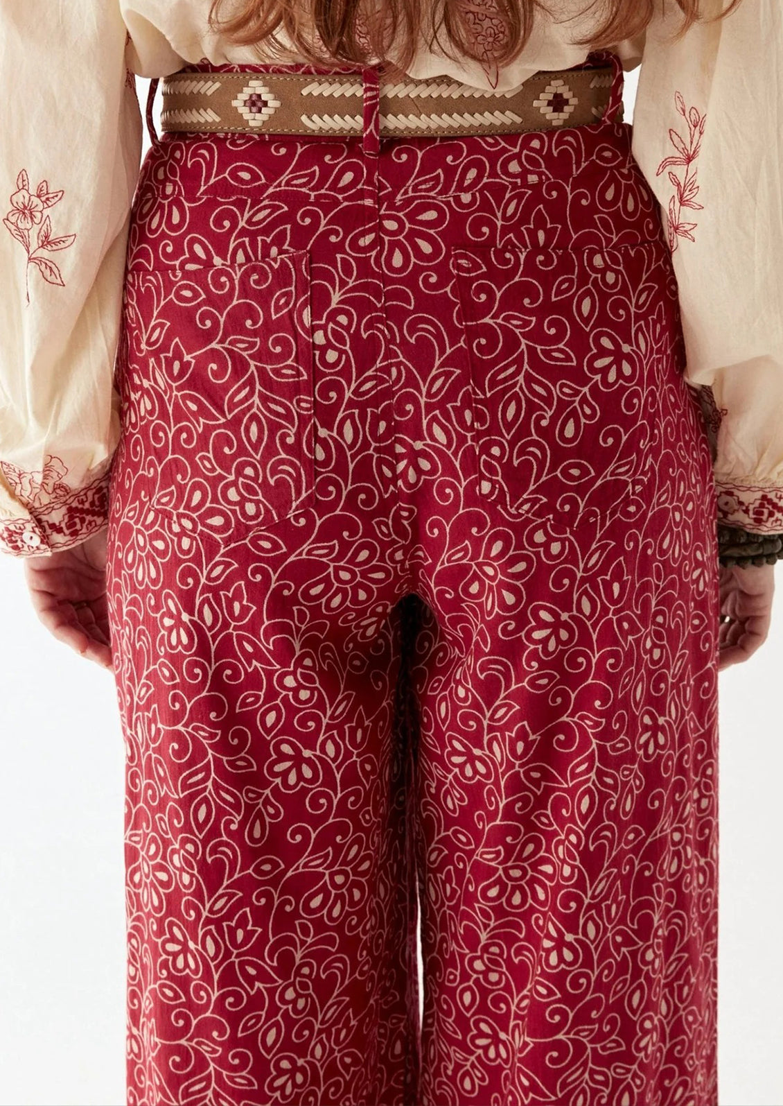 A person wearing a pair of red paisley patterned pants.