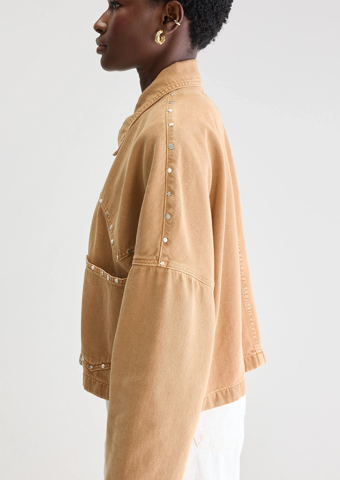 Person wearing a tan jacket with studded details.