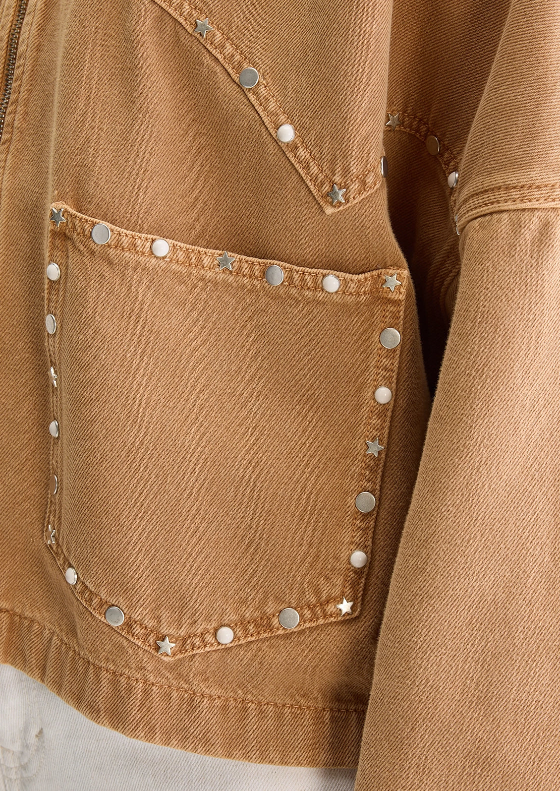 Person wearing a tan jacket with studded details.