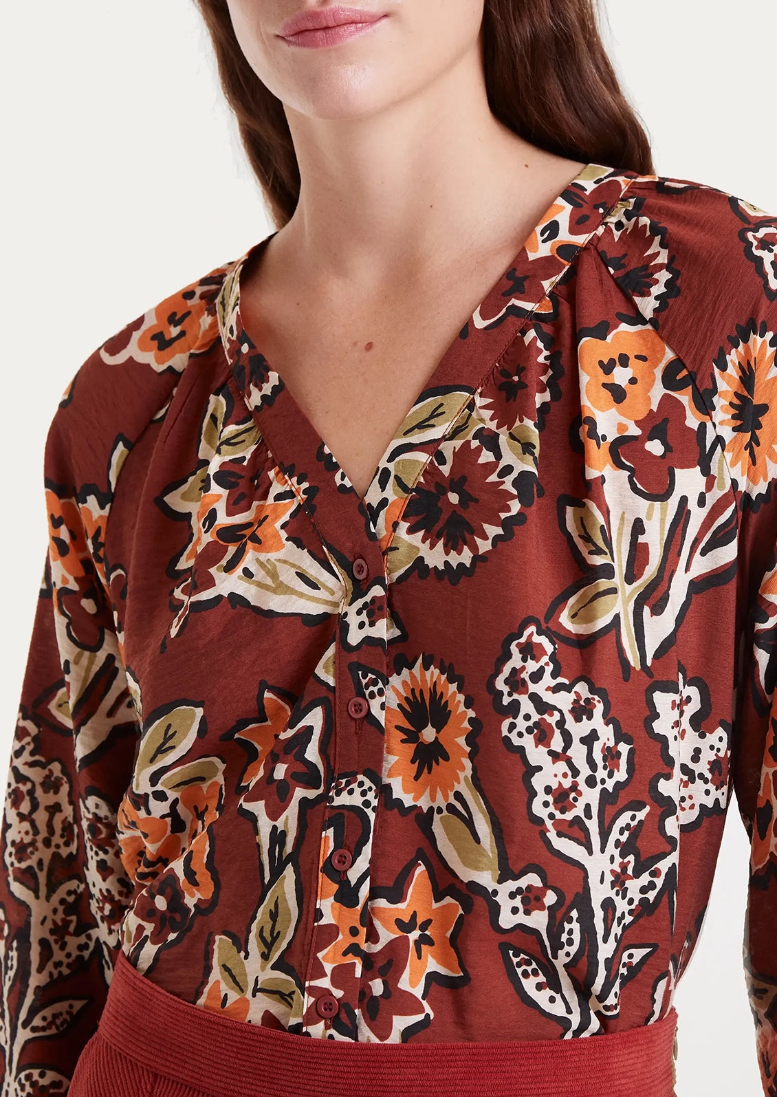 A floral print long sleeve blouse in rust with orange floral pattern.