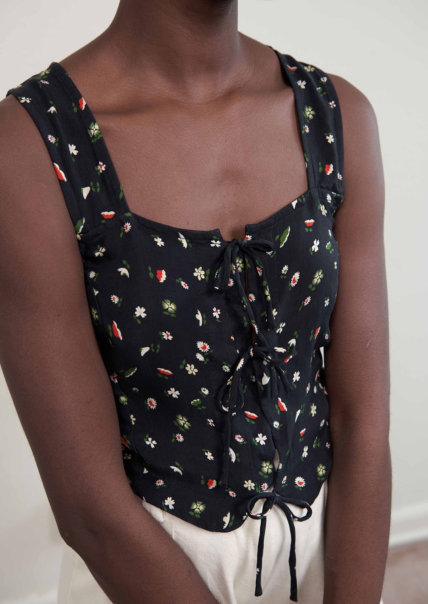 A woman wearing a black sleeveless tank top with multicolor flower print.