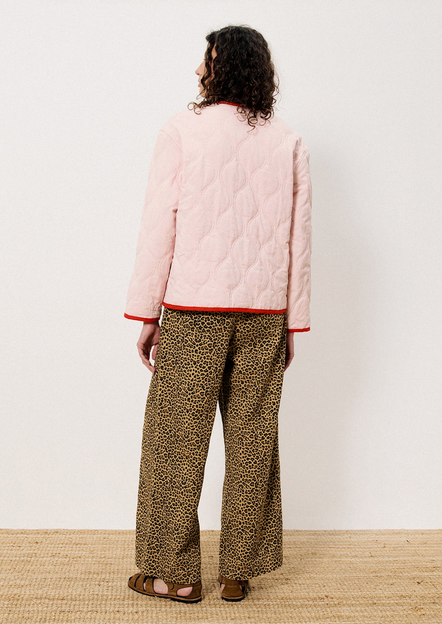 A person wearing a pink quilted jacket with red trim.