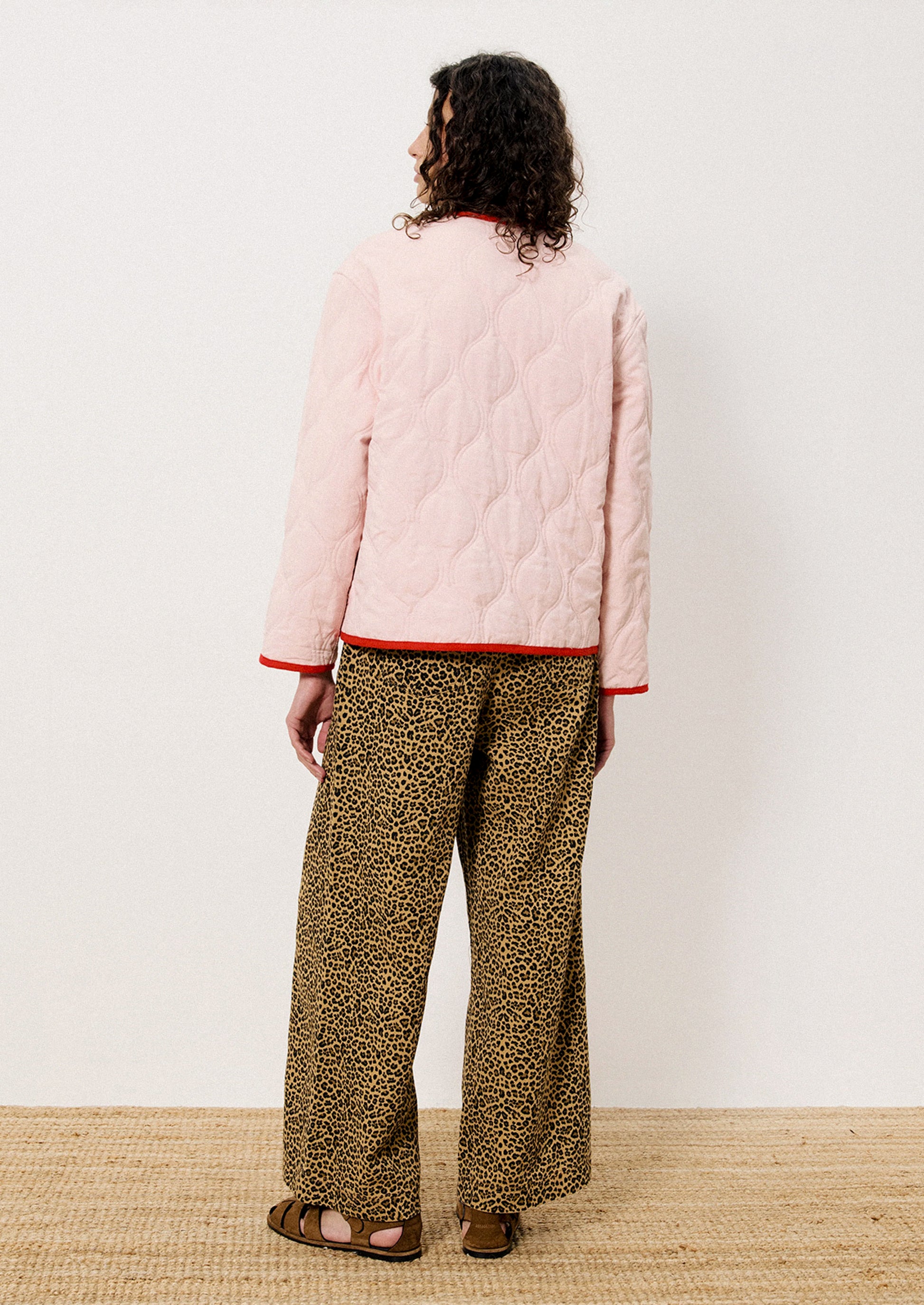 A person wearing a pink quilted jacket with red trim.