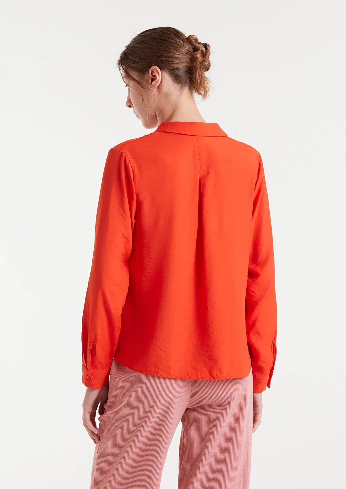 A person wearing a vibrant red-orange button up collared shirt.