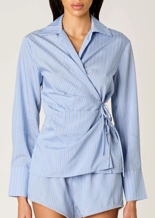 Woman wearing a blue and white striped wrap dress against a plain background