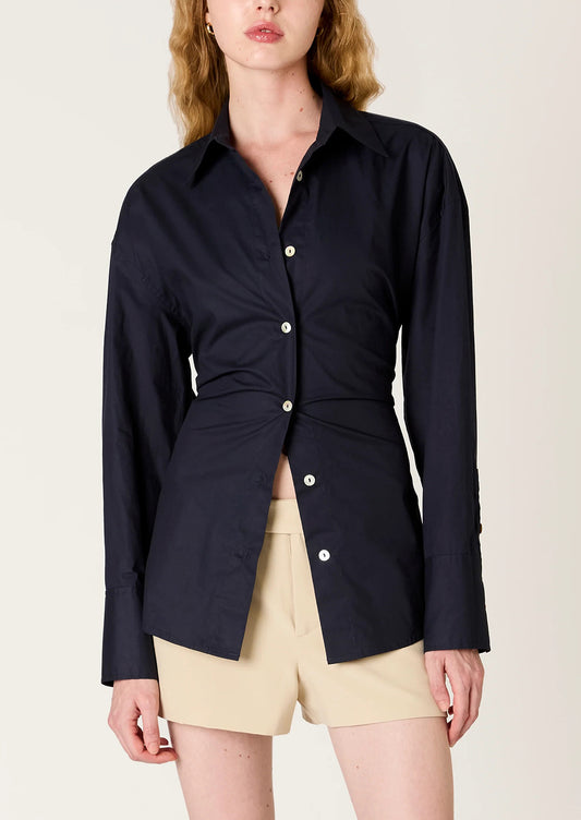 Woman wearing a navy blue shirt with a tie-waist design on a beige background
