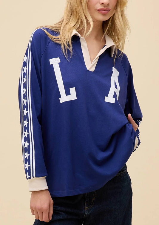 Person wearing a blue rugby shirt with white lettering on a beige background