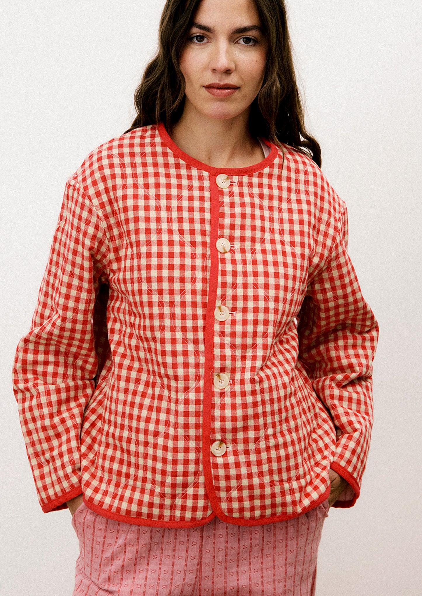 A person wearing a red and tan gingham quilted jacket with red trim.