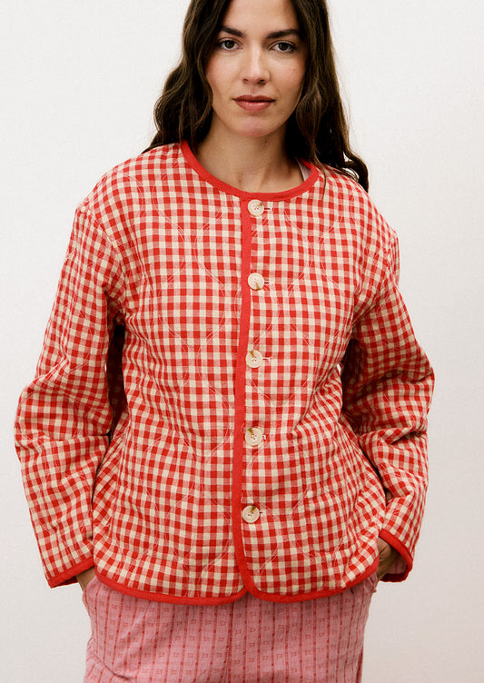 A person wearing a red and tan gingham quilted jacket with red trim.