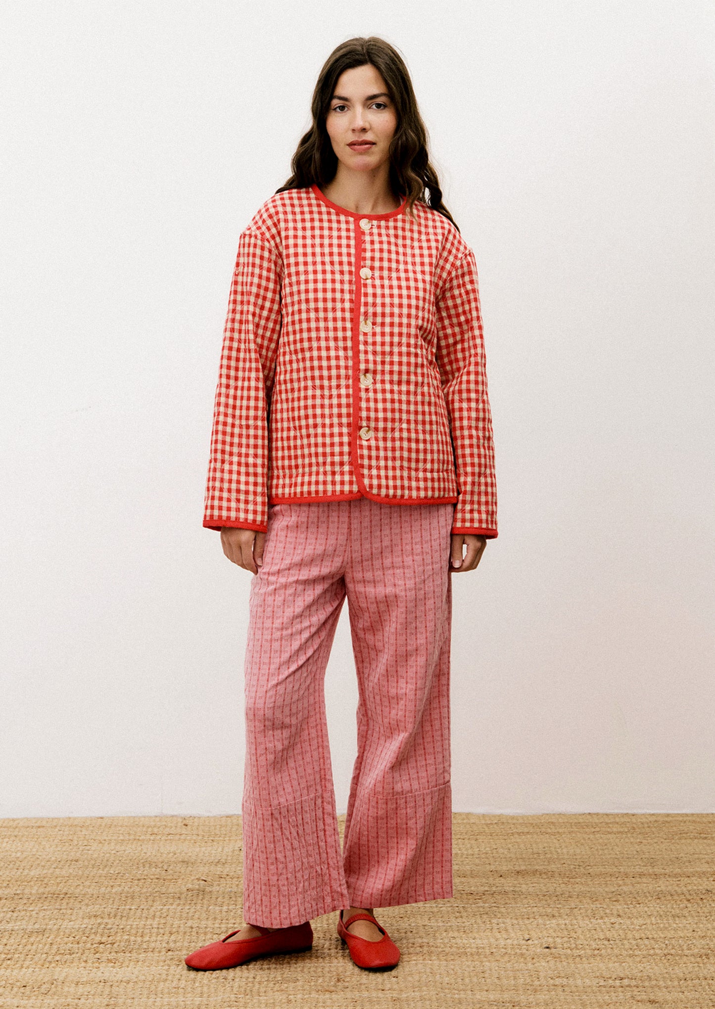 A person wearing a red and tan gingham quilted jacket with red trim.