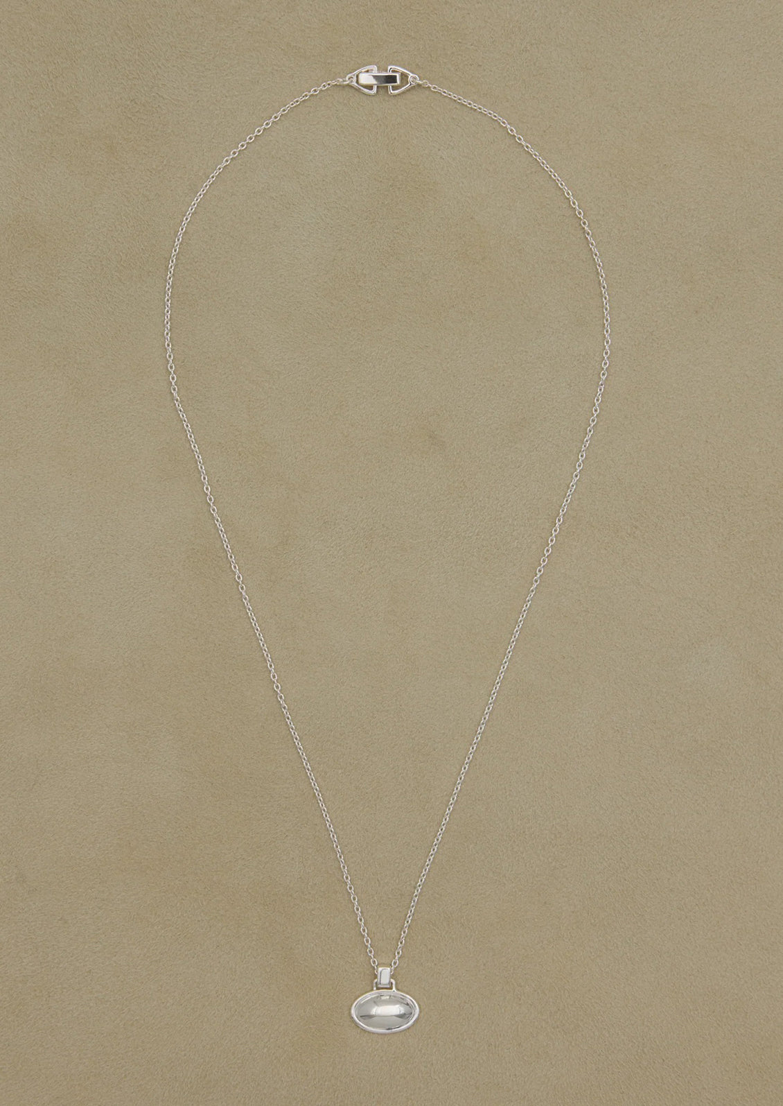 Silver necklace with a pendant on a beige background
