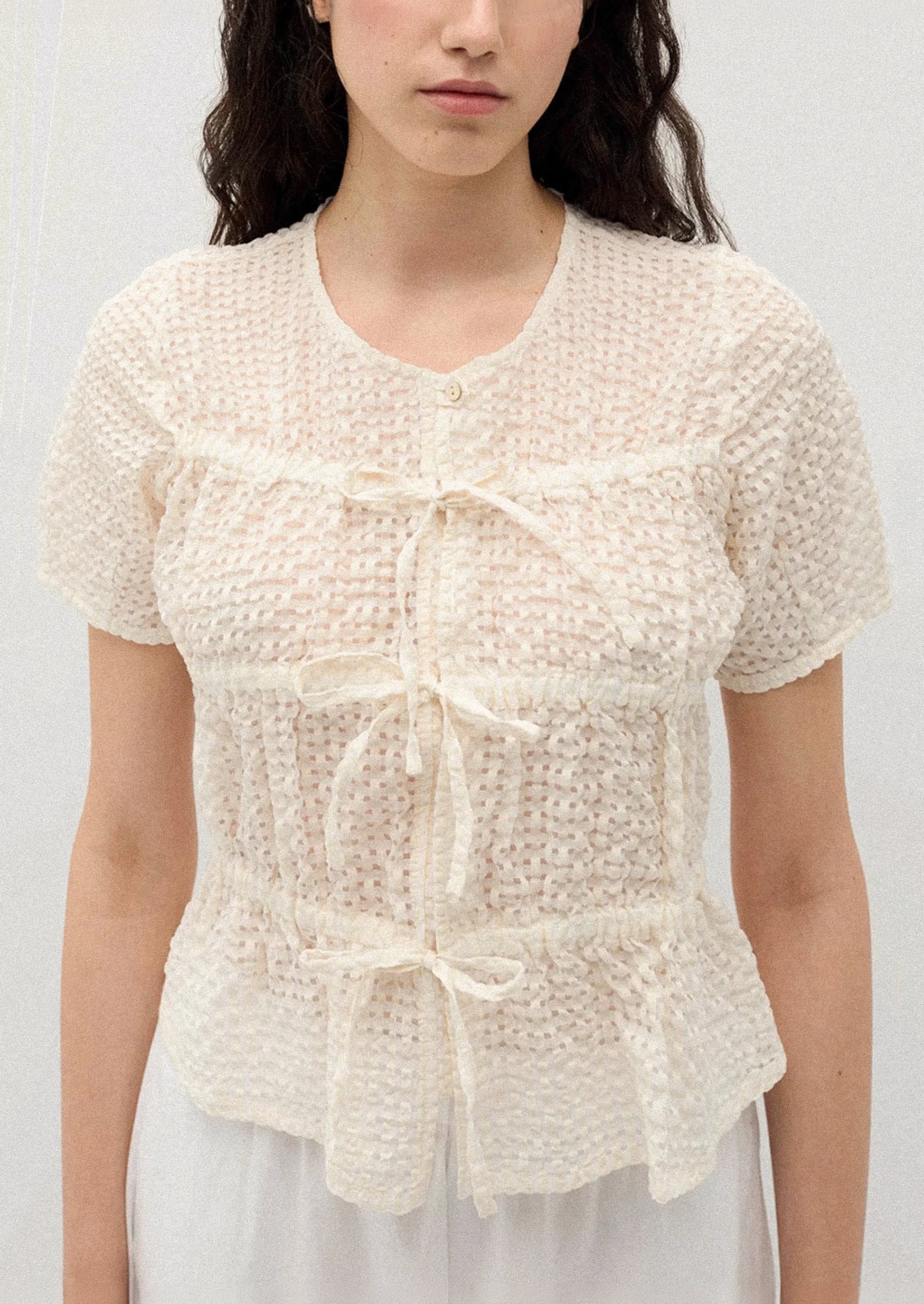 A person wearing a crinkled short sleeve top in cream.