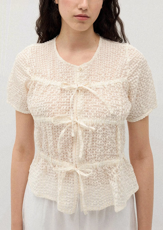 A person wearing a crinkled short sleeve top in cream.