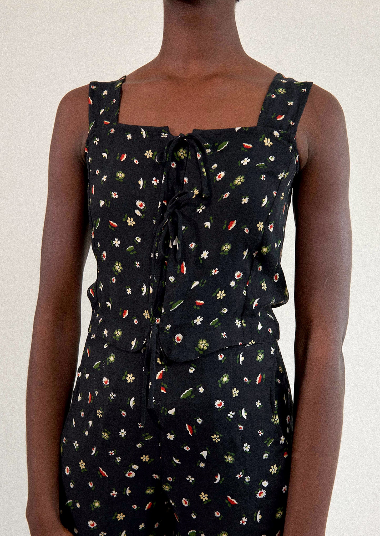 A woman wearing a black sleeveless tank top with multicolor flower print.