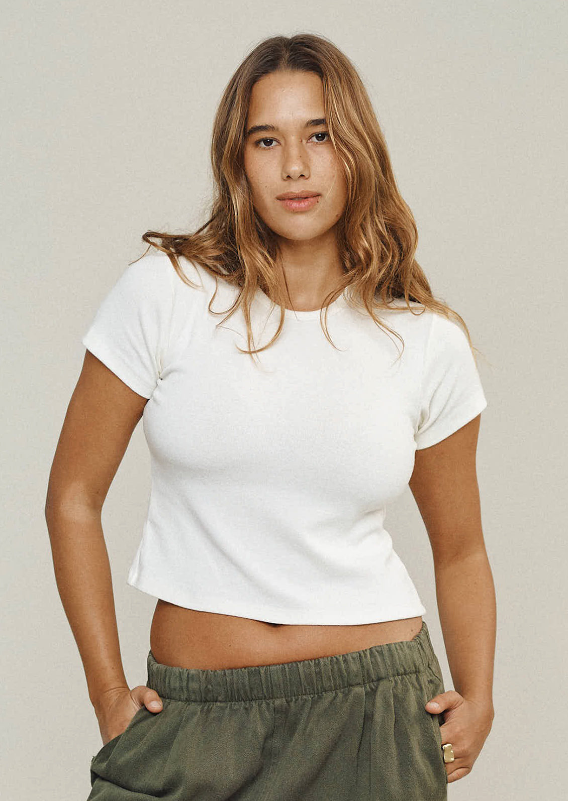 A person wearing a short sleeve baby tee in white.
