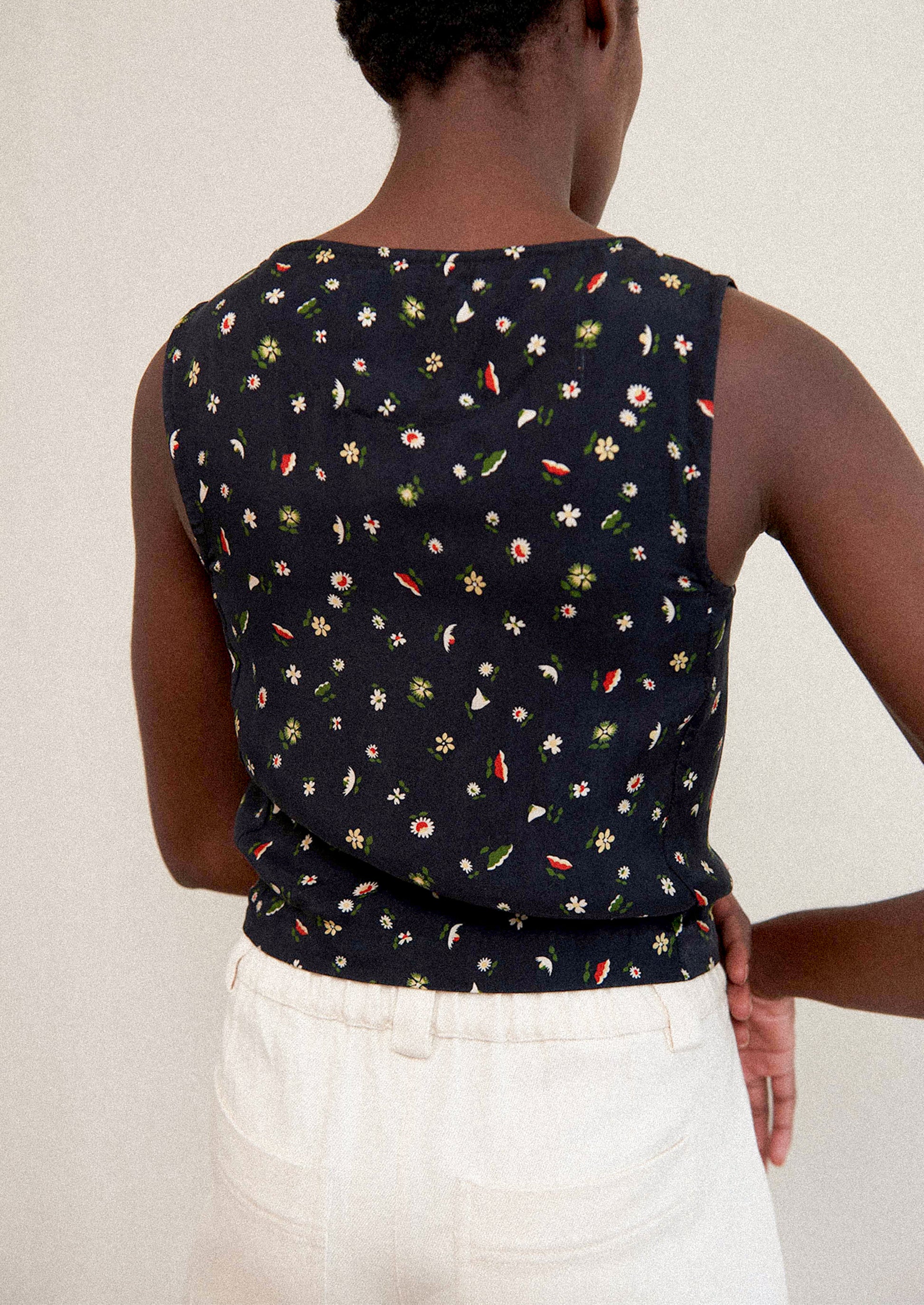 A woman wearing a black sleeveless tank top with multicolor flower print.