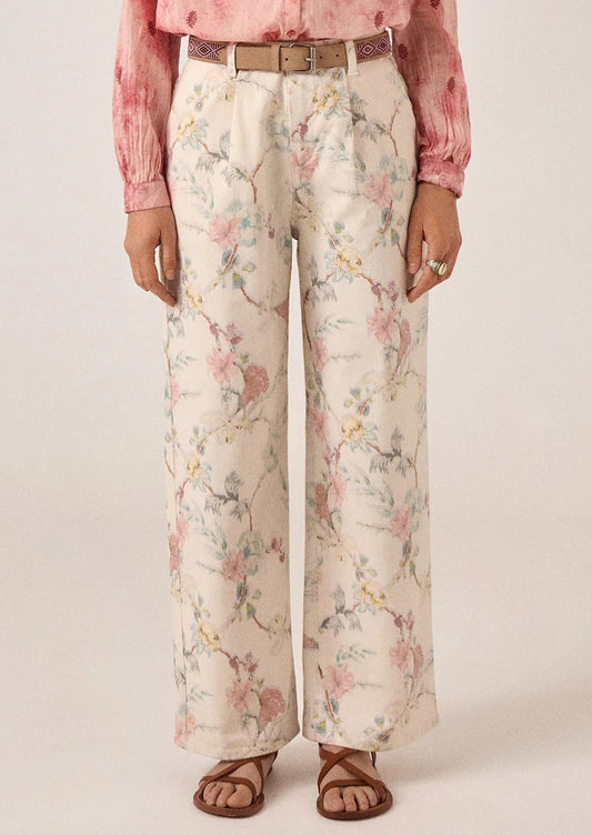 A person wearing a pair of white denim pants with pastel floral print.