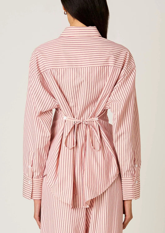 Person wearing a pink and white striped shirt and pants set on a plain background