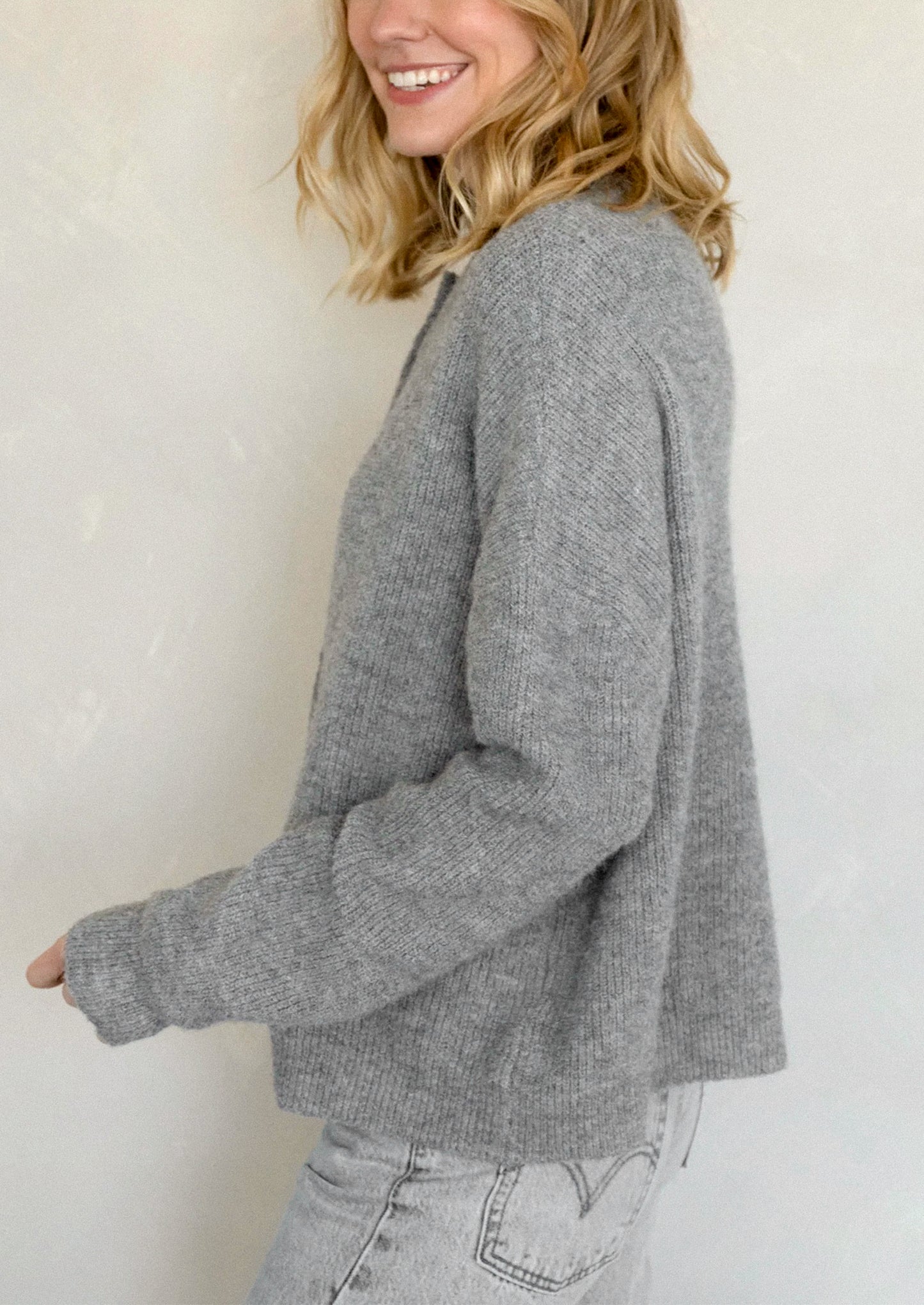 A woman wearing a heather grey cardigan with white button front.