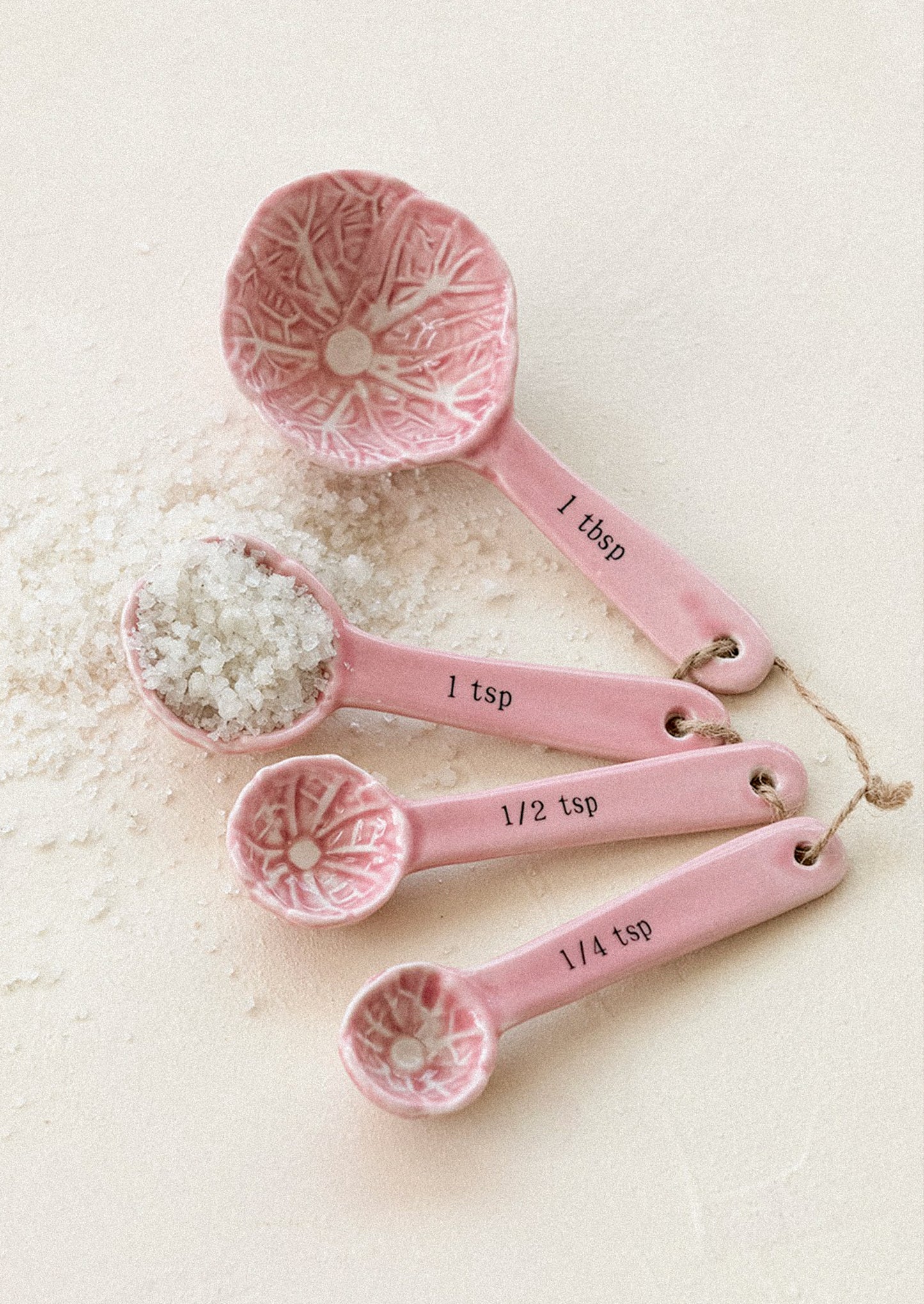 Set of pink ceramic measuring spoons on a white background