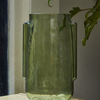 1: A transparent green glass vase in tall shape with side handle detail.