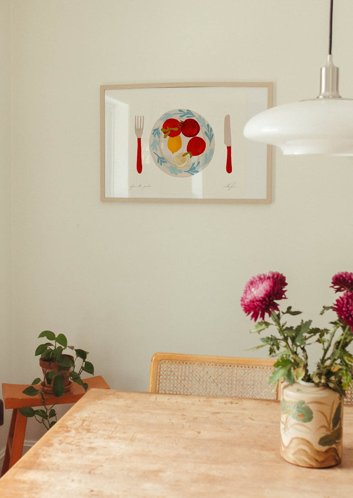 An art print of tomatoes and lemons on a plate with red knife and fork.