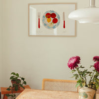 2: An art print of tomatoes and lemons on a plate with red knife and fork.