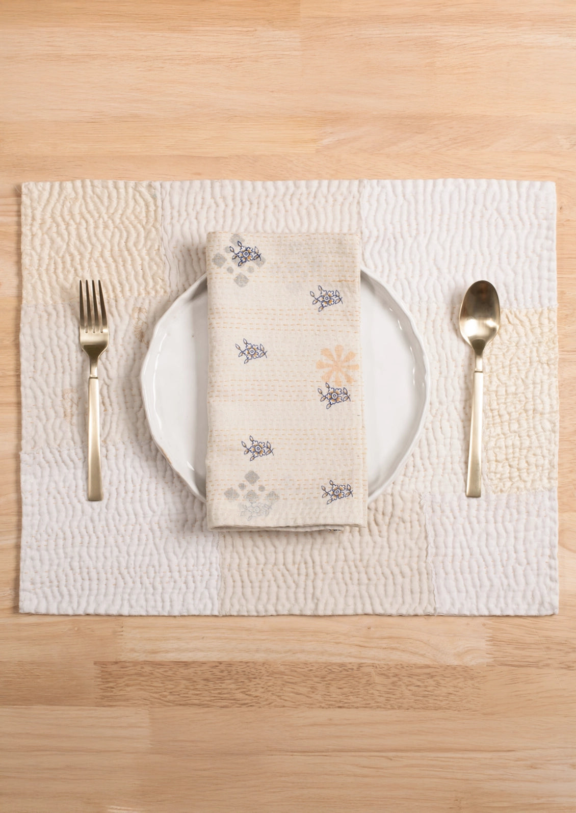 A patchwork placemat made from recycled vintage saris, in cream color palette.