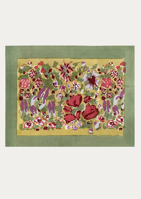 A block printed placemat with olive green border, and red, green and purple floral print on mustard at center.